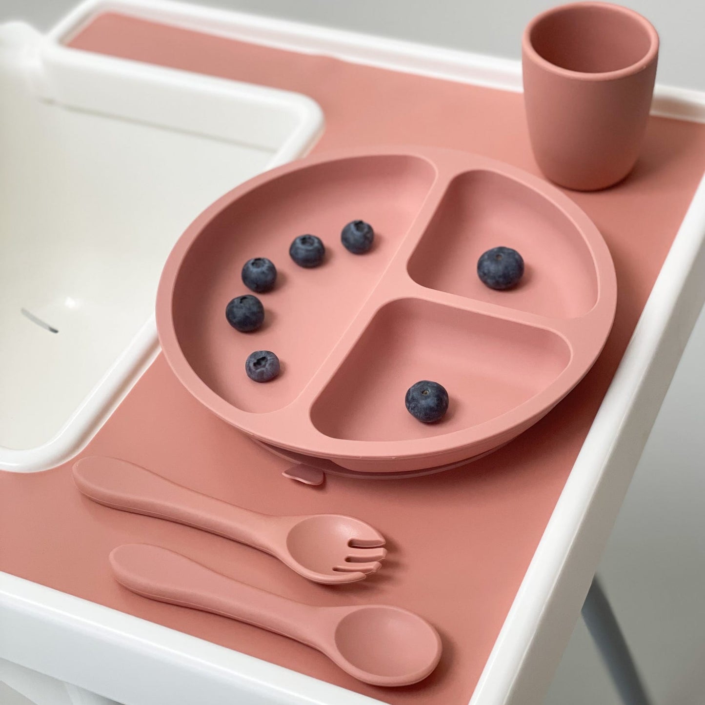 Silikon Teller mit 3 Fächern und Saugnapf für besseren Halt auf dem Tisch. Hier zu sehen der IKEA Hochstuhl mit passendem Tischset, dem 3 Fach Teller für Babys, Babybesteck und Becher. Alles in der Farbe rosa.